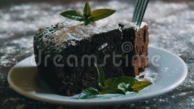 自制的烤巧克力巧克力蛋糕，在一个用薄荷叶装饰的白色盘子上裹着糖粉。 <strong>叉叉</strong>