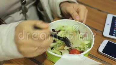 一位中年白人妇女在一个寒冷的夜晚坐在一家夏季咖啡馆的桌子旁，吃蔬菜沙拉和油炸食品