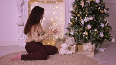 圣诞节壁炉旁美丽的年轻女子把礼物放在树下送给她的<strong>爱人</strong>。