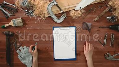 俯视图工匠双手拿着笔和夹纸板，放在桌上复印空间