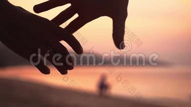 浪漫的情侣在令人惊叹的日落时分牵手在海滩上散步。 快乐的年轻夫妇享受海洋日落