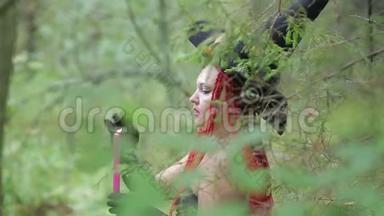 带着红色头发和尖尖帽子的迷人年轻女巫在森林里用蜡烛<strong>召唤</strong>