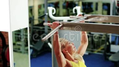运动的女人在健身房里，女孩做一个拉起来的运动，在水平杆上做运动，作为一个运动