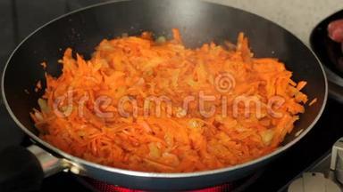 胡萝卜加洋葱在煎锅里油炸。放在电炉上的煎锅里的果汁沸腾了。