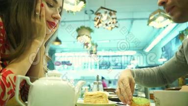 快乐的一对夫妇在咖啡馆吃甜点。 带着蛋糕的雷鬼女孩