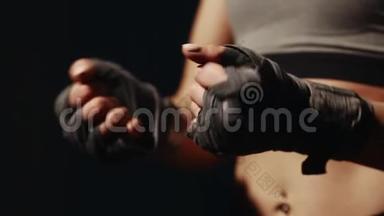 在比赛前，女孩自己用绷带在黑色背景上包扎他的手。 准备战斗。 特写