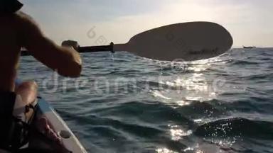 在开阔的海水中，在皮艇上看到强壮的男人。 落山悬崖上的日落。 莱利海滩，克拉比，泰国。