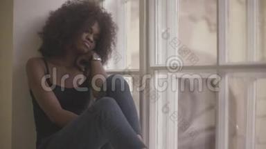 美丽而<strong>悲伤</strong>的年轻非洲女人坐在窗台上<strong>悲伤</strong>
