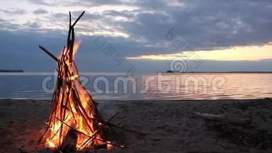 日落时分在河岸燃烧的帐篷形式的篝火
