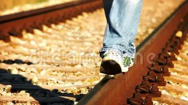 一个穿着牛仔裤和运动鞋的少年在铁轨上行走的加速镜头