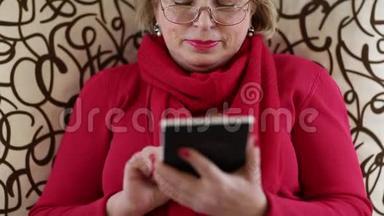 女人坐在沙发上用电子书。 带电子书的女人