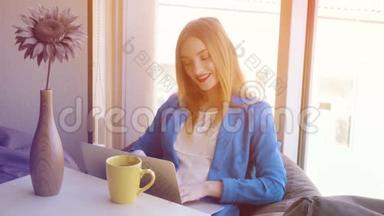 穿蓝色夹克的女孩在沙发上用笔记本电脑工作