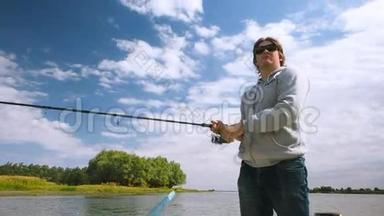渔夫从河上的一艘船上钓到一条鱼。 在伏尔加河三角洲的船上钓鱼的人