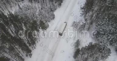 卡车在雪林的冬季乡村道路上行驶。 空中镜头。