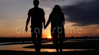 恋爱中的情侣在河边散步，在日落时牵手。 高清，1920x1080。 慢动作。