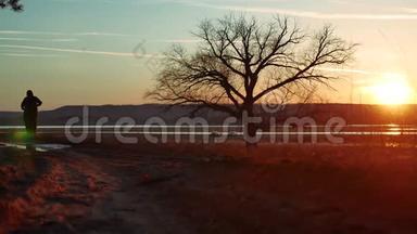 剪影两人在夕阳下的路上独自站在树上剪影。 运动青年在生活方式中奔跑