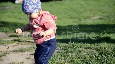 微笑可爱好玩的小女孩站在绿草上。 女孩蹒跚学步在湖边散步，学会走路。 阳光明媚