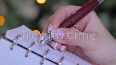 女人手拿笔写字，在老式笔记本电脑组织者做清单