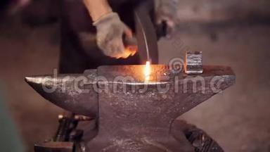 铁匠用锤子和热红金属加工。 两个人在铁匠铺的铁砧上锻造铁。