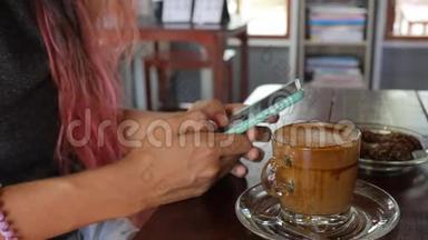 混合种族亚洲妇女与彩色头发使用移动应用程序智能手机在咖啡厅，喝咖啡和短信。 <strong>高清高清</strong>