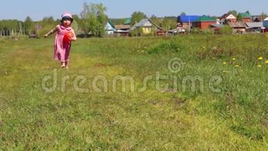 快乐的小女孩带着球来到村庄附近的绿色草地上
