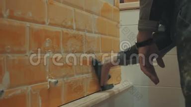 男`的手把墙上橘色瓷砖上的残余腻子洗掉了