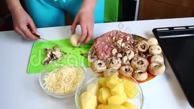 一个女人在切割板上切了新鲜的香瓜。 桌子旁边有极好的土豆、烤盘、多汁的切碎机和切碎机
