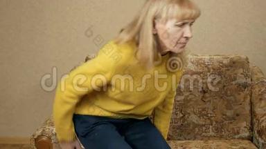 年老的女人不能从沙发上爬下来，因为房子后面的疼痛。 她坐在后面做腰椎按摩