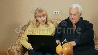 老夫妇学习如何使用笔记本电脑。 一个男人展示如何做。 女人笑着跟在他后面重复。 老年人