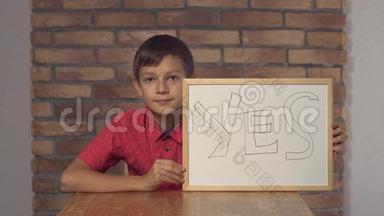 坐在书桌前的孩子拿着一张挂图，在背景红砖墙上刻着yea。