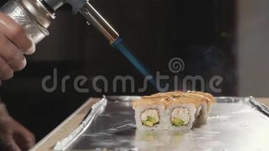 专业寿司厨师在商业厨房通过火准备卷，特写。