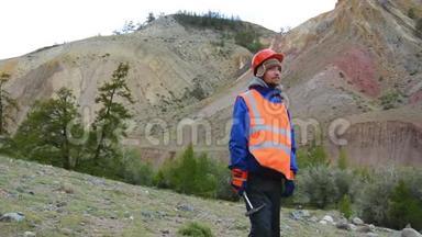 采矿工程师的肖像，穿着防护反光背心的地质学家，手套和头盔，手里拿着锤子。