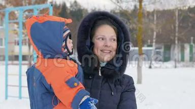 婴儿在他<strong>妈妈怀里</strong>`冬天在公园里。 他们热情地穿着衣服，母亲和她的儿子说话。 一个英俊的男孩