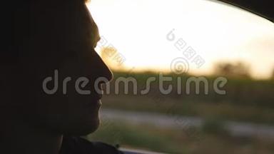 年轻英俊的男人在日落时开车。 在户外夕阳下开车的人。 孩子在里面