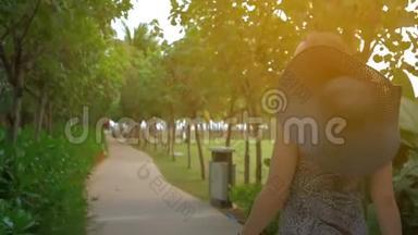 戴着蓝帽子的年轻女孩正穿过一个热带公园。 夏日时光。 慢动作。