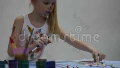 小女生。 可爱的小女孩画家在桌子上<strong>画画</strong>，在她的衣服上<strong>画画</strong>。 慢动作