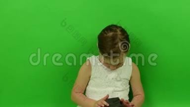可爱的小女孩在色度键背景上使用手机。 穿着浪漫裙子的小女孩。 白色<strong>婚纱礼服</strong>