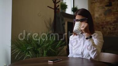 一个漂亮的学生女孩在<strong>校长</strong>里唱咖啡，并在电话上给她的男朋友写短信。 a行