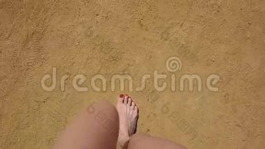 她脚上有红色指甲的女孩踩着沙子