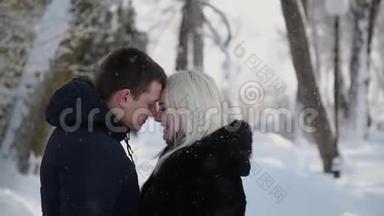美丽的年轻夫妇<strong>牵着</strong>手在一个城市冬季公园里交谈和微笑。