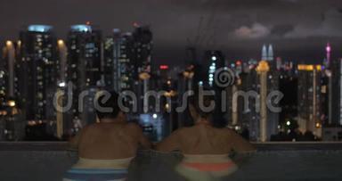 马来西亚吉隆坡一家酒店的屋顶上有一个游泳池，男人和女人<strong>一起去</strong>夜城
