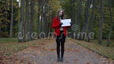 <strong>美丽</strong>的白种人女人，穿着红色外套，在秋天的森林里，用纸出售<strong>标语</strong>牌