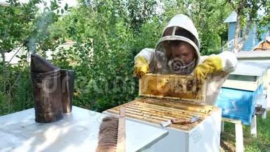 在蜂巢附近穿着防护服的快乐男孩养蜂人。 有蜂蜜的蜂窝。 有机食品概念。 最有用的