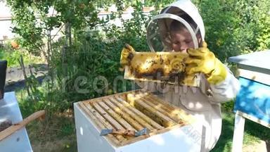 在蜂巢附近穿着防护服的快乐男孩养蜂人。 有蜂蜜的蜂窝。 有机食品概念。 最有用的