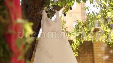 婚礼婚纱挂在一棵树上的乡村风格的婚礼。 带有粉红色花束、花环和乡村装饰