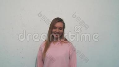 穿着粉色运动衫的漂亮女人在白色背景上为相机微笑