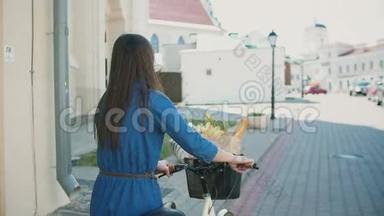 一个挥舞着头发的女孩走在自行车上，带着花和面包在篮子里，慢<strong>悠悠</strong>，稳定的镜头