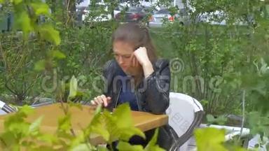 悲伤的漂亮女孩坐在咖啡馆的桌子旁。 在智能手机上读取短信。 悲伤和渴望，绝望。