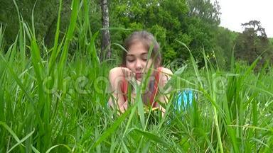 轻松的小女孩在田里看书。 <strong>可爱</strong>的少年躺在草地上。 视频镜头<strong>高清</strong>拍摄静态