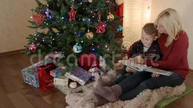 快乐的母子坐在圣诞树下翻着相册